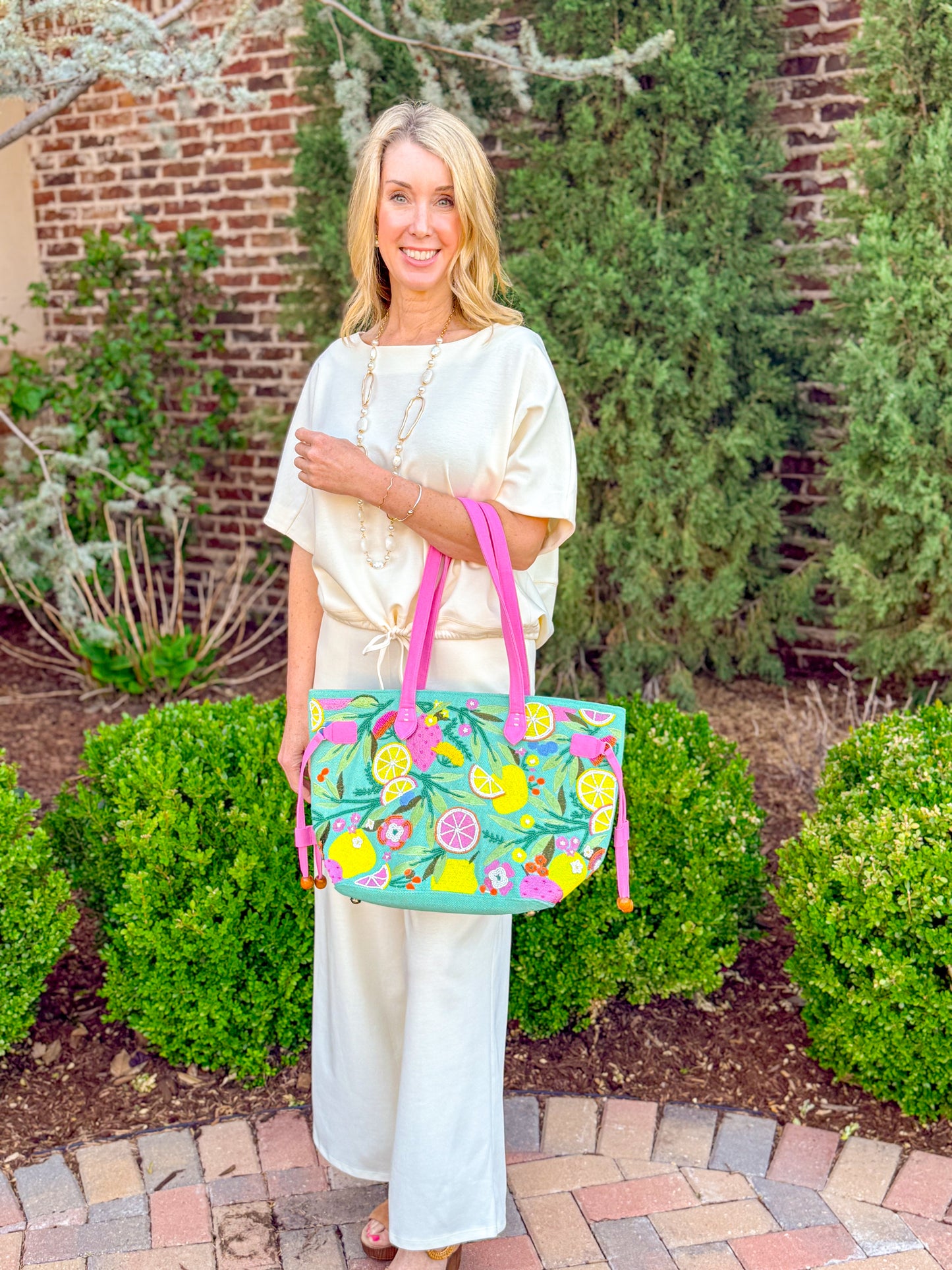 Cream knit drawstring waist lounge set styled with colorful embroidered citrus tote bag and sandals, elevated casual boutique outfit inspiration