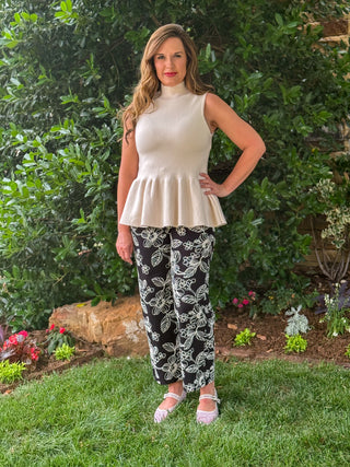 Women's black cropped pants with ivory floral embroidery and gold button accents, styled with a cream sleeveless peplum top for a chic boutique outfit