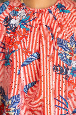 Woman wearing red and white striped embroidered floral raglan sleeve top with round neckline and button detail
