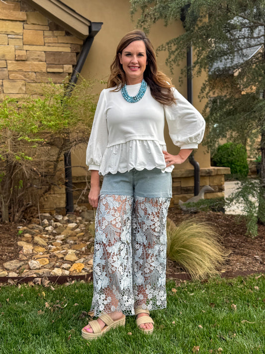 Women’s white long sleeve peplum top with balloon sleeves paired with denim and layered blue bead necklace casual boutique outfit