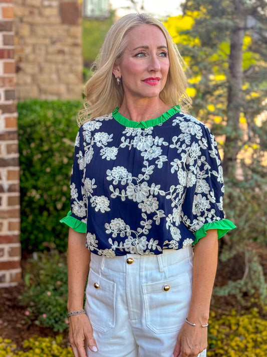 Navy floral embroidered blouse with green ruffle neckline and sleeve detail, styled tucked into high waist ivory culottes, boutique outfit inspiration