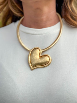 Gold heart statement necklace with oversized textured pendant on structured collar for women’s boutique fashion