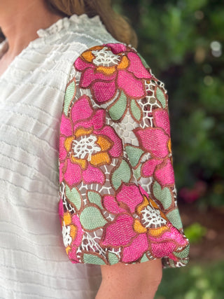 Close-up detail of pink floral embroidered lace puff sleeve on an ivory textured blouse, showcasing intricate embroidery and dimensional floral design.
