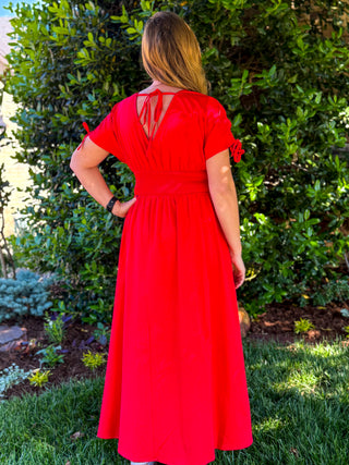 Red midi dress back view featuring smocked waist, tie back neckline, and short sleeves ideal for spring events and everyday wear