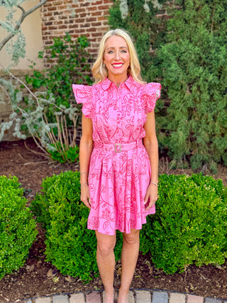 Pink floral eyelet mini dress with ruffle sleeves, button front, and belted waist shown from the front