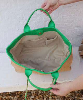 Interior of straw tote showing zipper pocket and compartments with kelly green trim