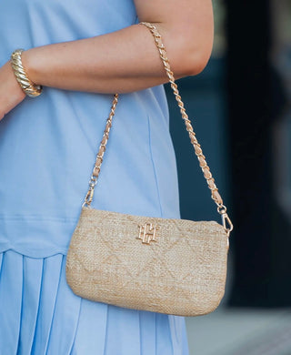 Neutral woven crossbody purse with gold chain strap and textured finish styled with a light blue dress