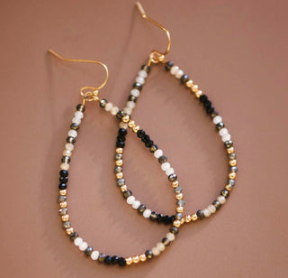 Mixed glass crystal teardrop dangle earrings with black, ivory, gray, and gold beads on gold wire hooks.
