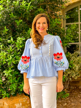 Blue stripe embroidered floral puff sleeve top styled with white pants, boutique spring outfit with red floral sleeve detail and relaxed fit